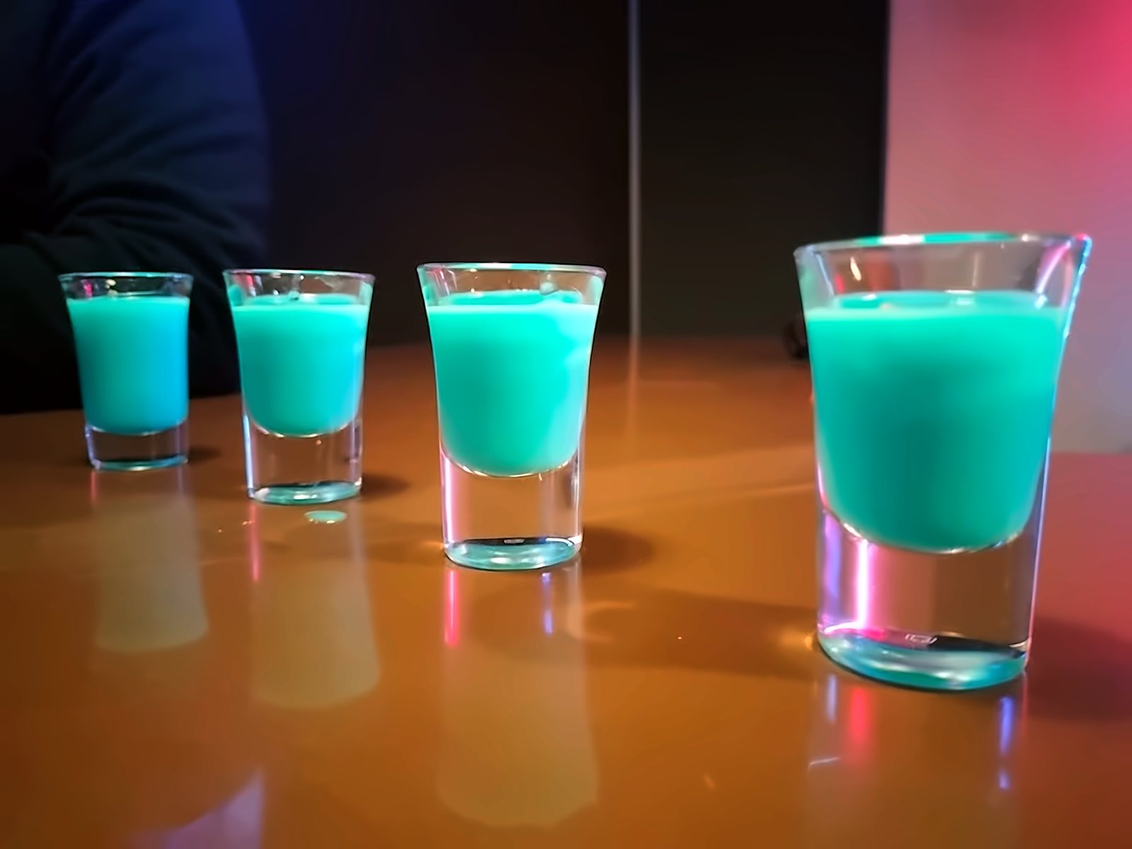 Cuatro chupitos turquesa sobre la barra