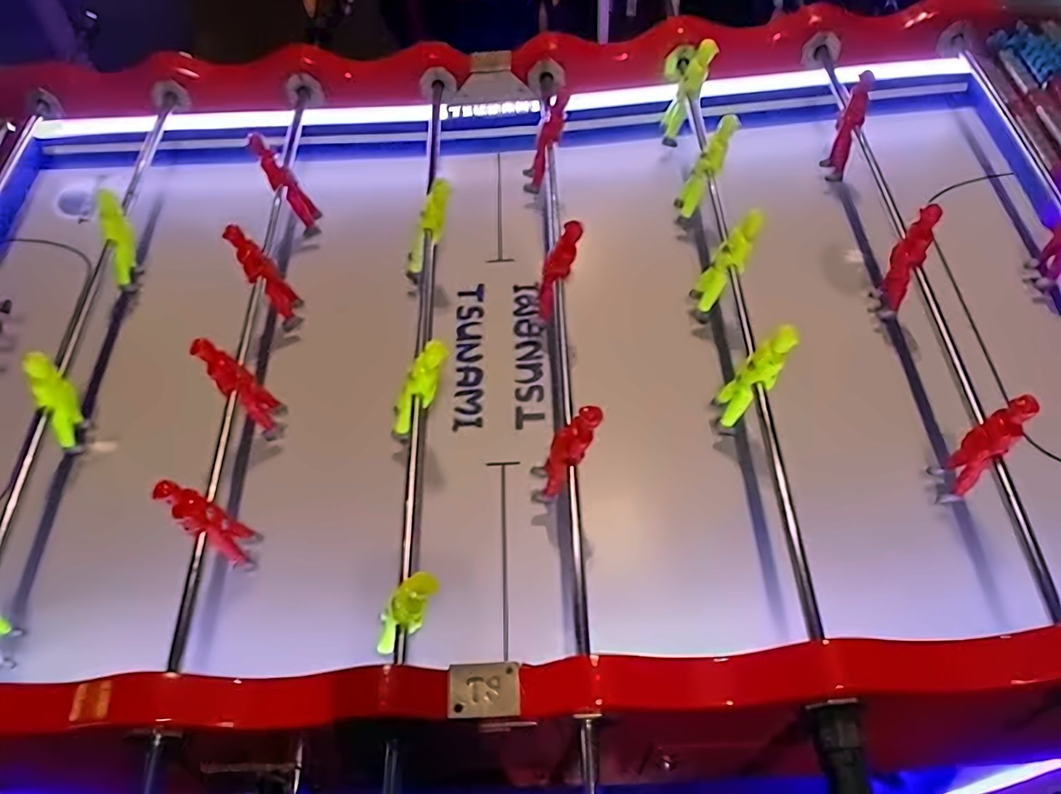 Futbolín del Raspabar con jugadores rojos y amarillos y luces de neón azul